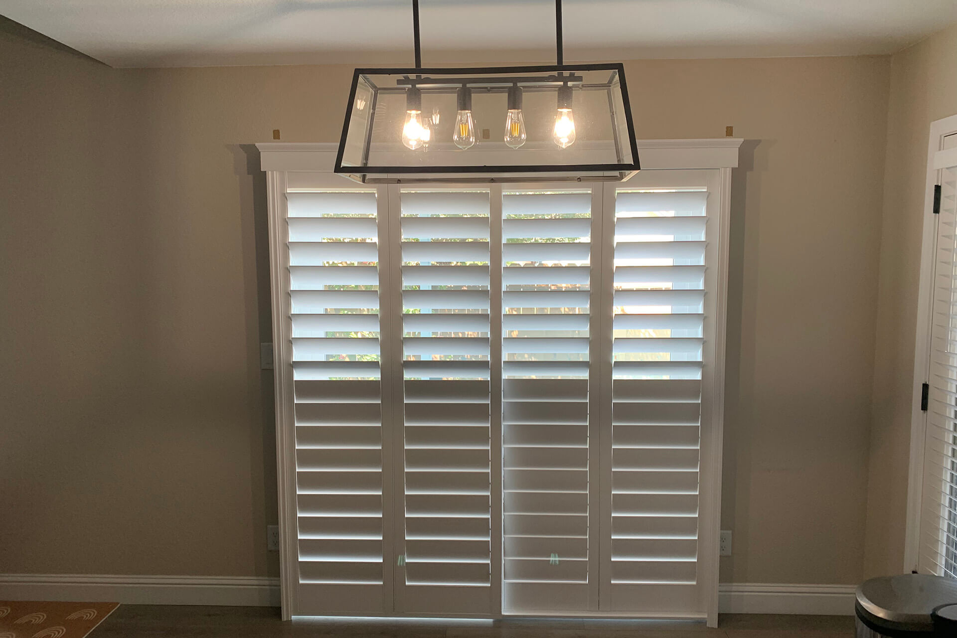 A set of plantation shutter doors that cover the sliding doors to a backyard.