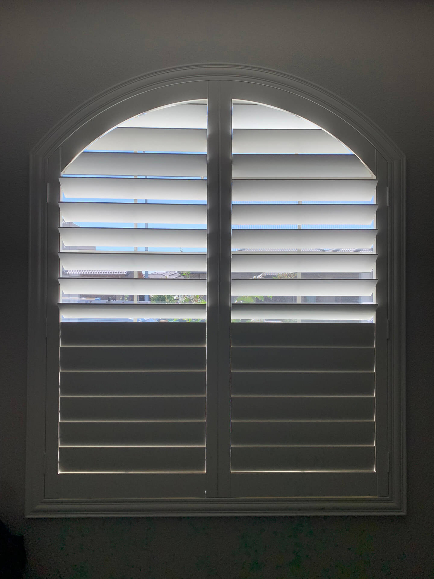 A single arched window completely covered with shutters.