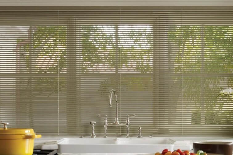 A kitchen with a wall of windows covered by aluminum blinds.