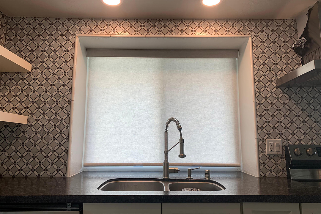 A kitchen with a roller shade behind the sink pulled all the way down.