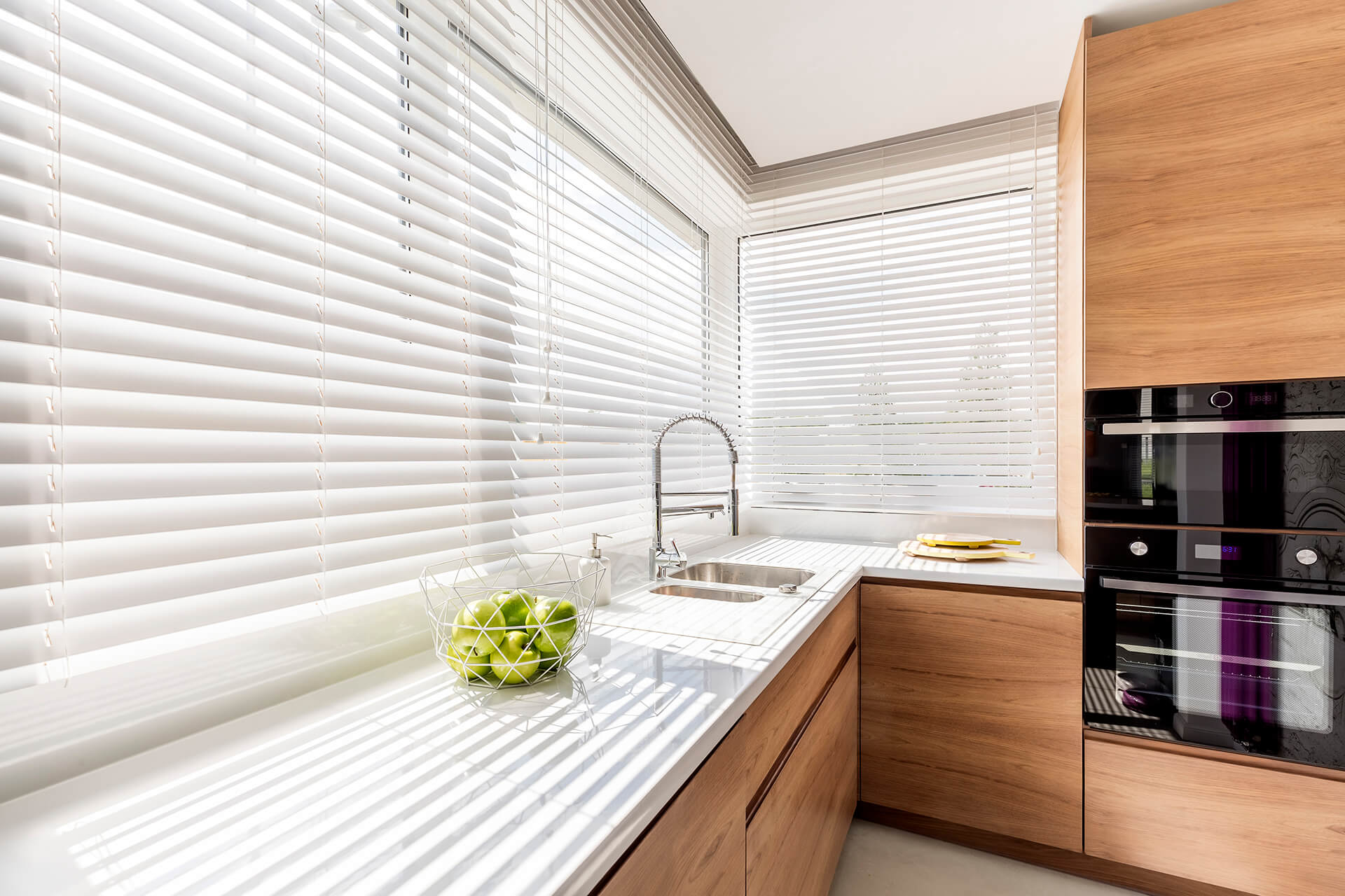Clean white and wooden kitchen with half open blinds.