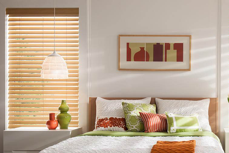An orange and green themed bedroom with orange shades covering a window