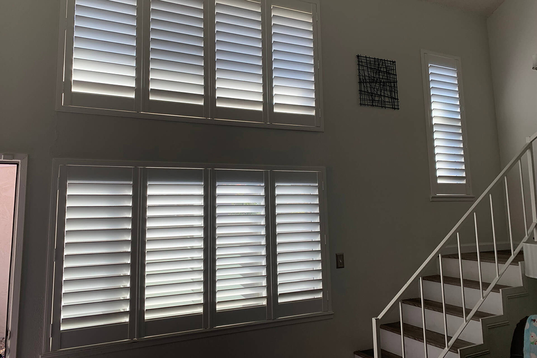 An empty wall of windows near stairs with shutters covering all windows.